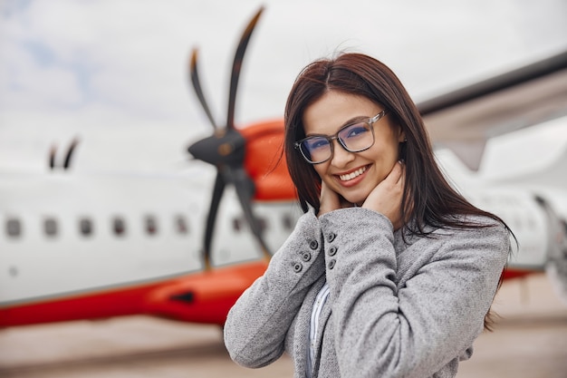 Кавказская счастливая женщина улыбается возле самолета перед посадкой