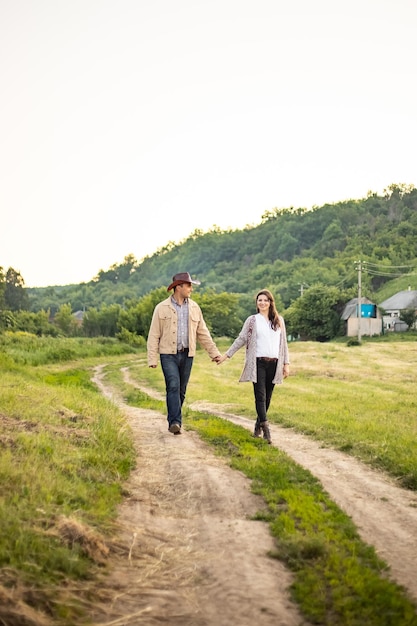 A Caucasian heterosexual couple walks down the alley holding hands near a picturesque village in Ukraine Vertical photo