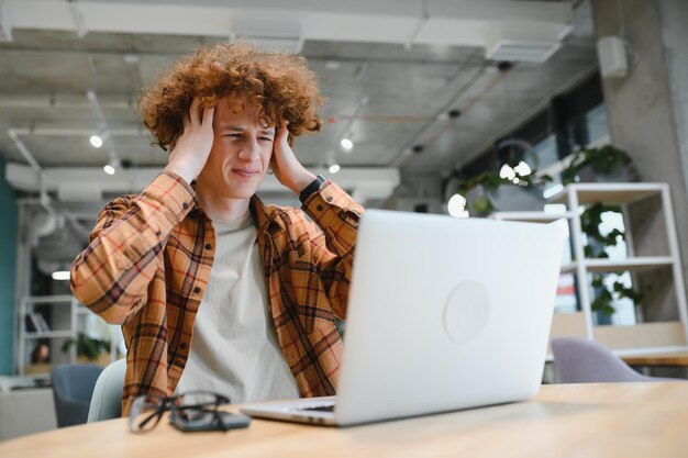 Photo caucasian hipster guy enjoying distance job in coffee shop male freelancer in trendy glasses sitting in cafeteria with modern laptop device