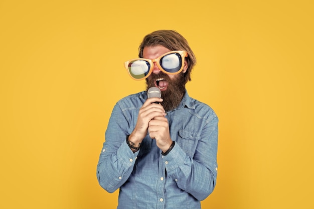 Caucasian hipster with beard and stylish hair in arty glasses with microphone music