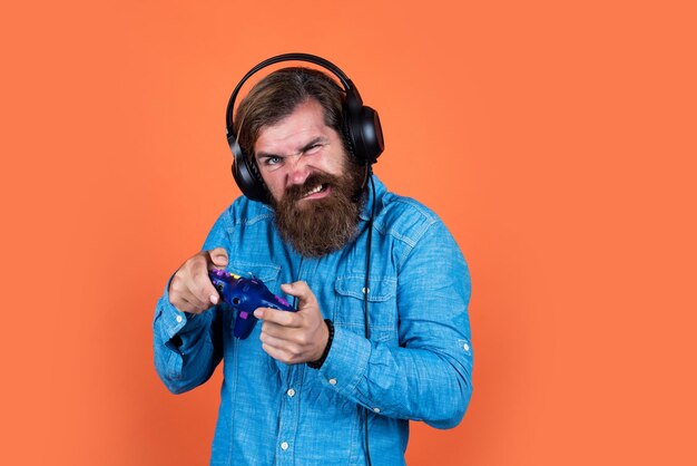 Кавказский хипстер с бородой и стильными волосами в наушниках с игровой приставкой современная жизнь