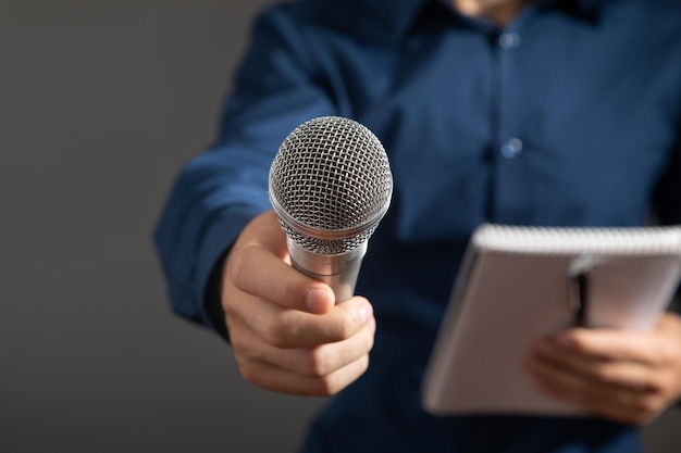 Caucasian journalist holding microphone notepad and pen