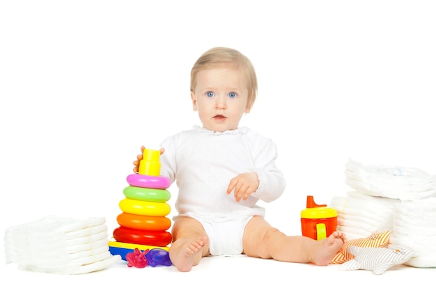 Caucasian kid with stacked diapers and toys isolated on white background