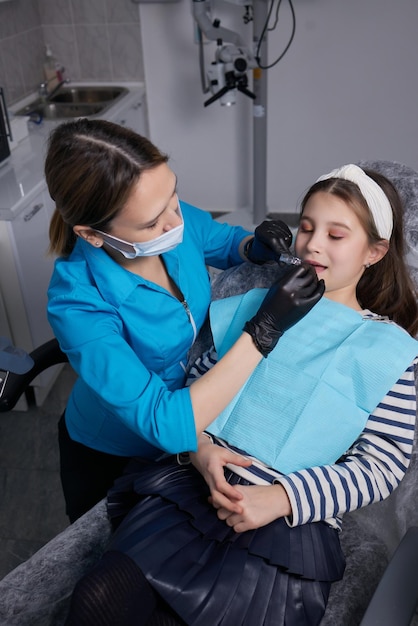 Caucasian little kid girl invisible aligner and pointing to her perfect straight teeth. Dental healthcare and confidence concept.