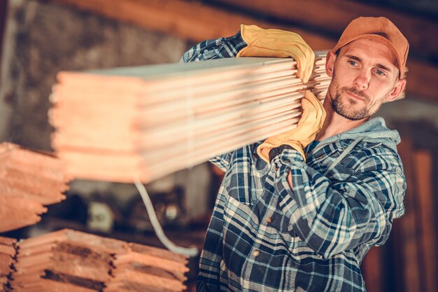 Foto imprenditore del legname caucasico di trent'anni con tavole di legno sulla sua spalla tema di costruzione