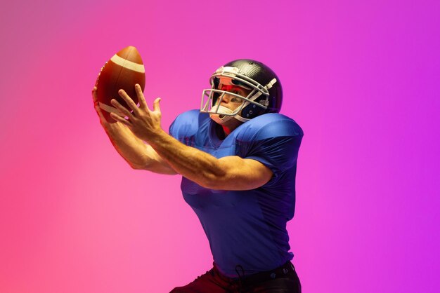 Photo caucasian male american football player holding ball with neon pink lighting