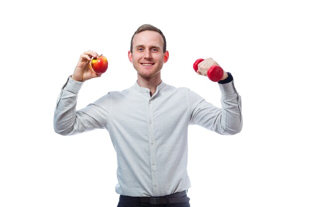 Caucasian male businessman holding a red-yellow apple and red dumbbell. He is wearing a shirt. Emotional portrait. Isolated on white background