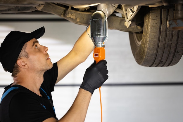 Caucasian male car mechanic checking car auto mechanic working underneath car lifting machine