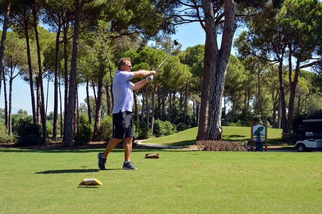 A Caucasian male hits a golf ball near the hole on the green of a private golf club