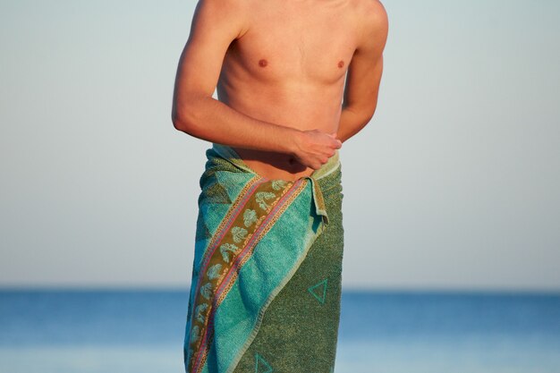 A caucasian male's body wrapped in a green towel with a blurred background