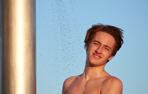 Un maschio caucasico che fa la doccia in spiaggia durante il giorno