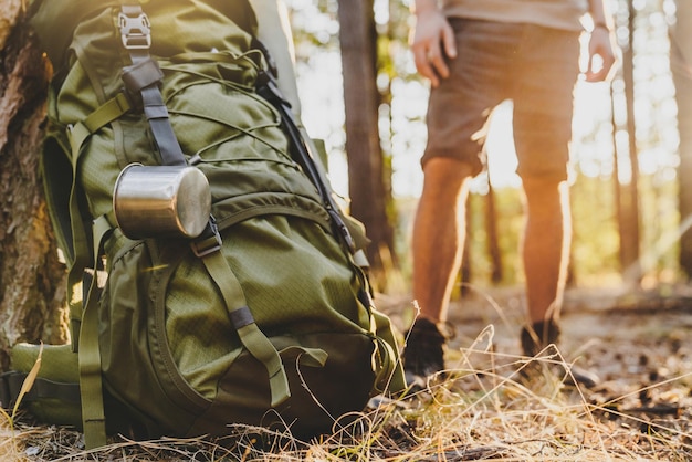 Caucasian male traveler standing near backpack while traveling in forest Travelling concept