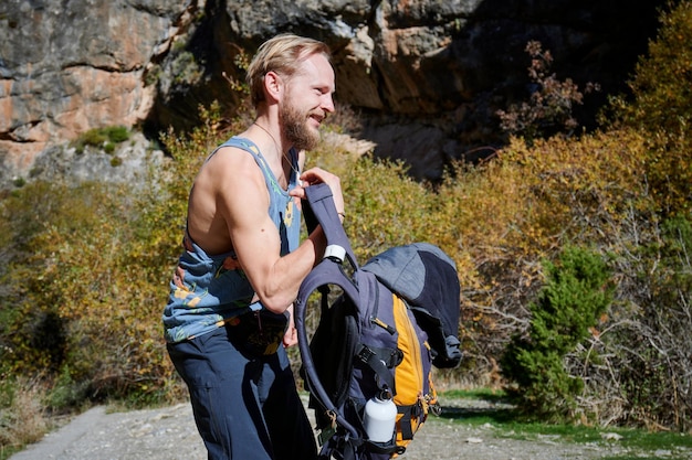 A Caucasian male with a backpack hiking on a sunny day in the mountain
