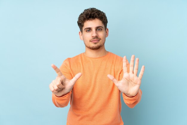 Uomo caucasico sul blu contando sette con le dita