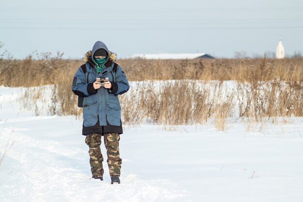 Caucasian Man in the blue jacket launching a flying drone with a remote controller