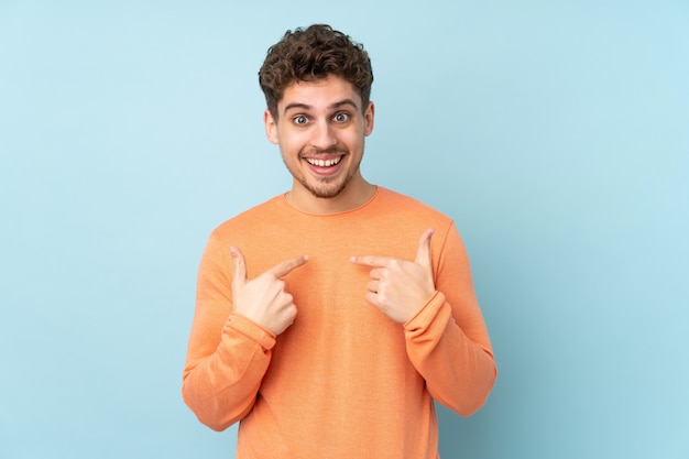 Uomo caucasico sulla parete blu con espressione facciale a sorpresa