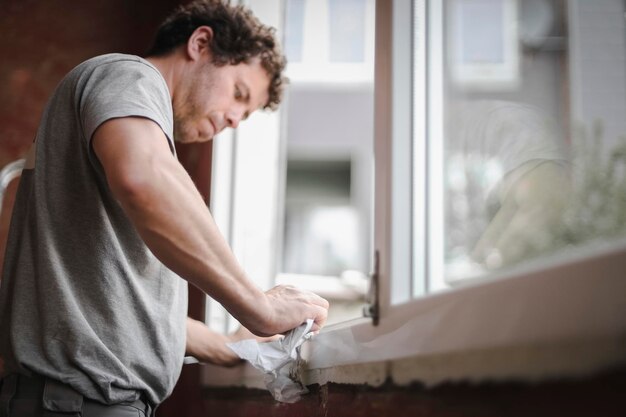 Caucasian man cleans the window frame