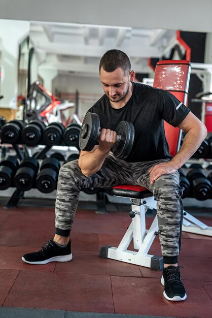 Caucasian man doing workout with dumbbells in gym