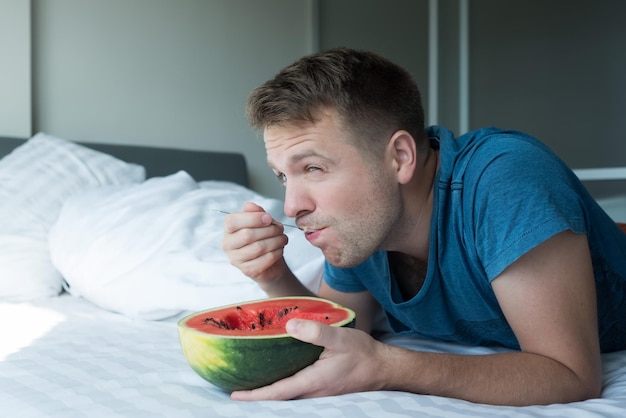 家でスイカを食べる白人男性