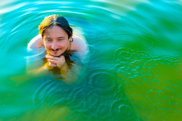 Caucasian man floating in a swimming lake with blue water
