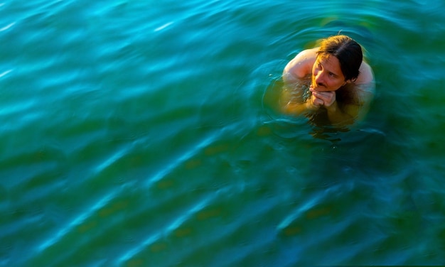 Caucasian man floating in a swimming lake with blue water