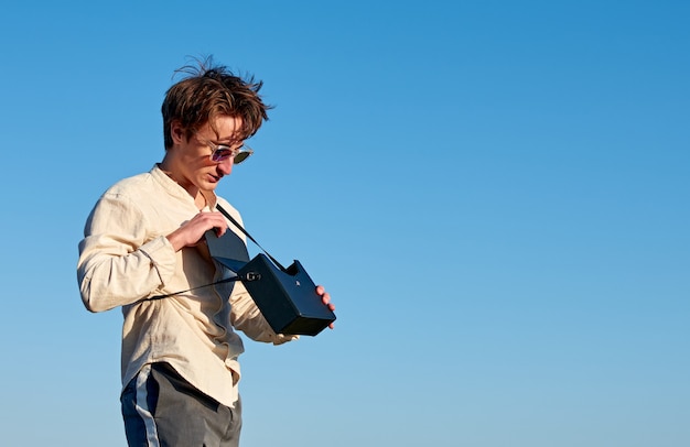 A Caucasian man from Spain standing and opening his black handbag on sky background