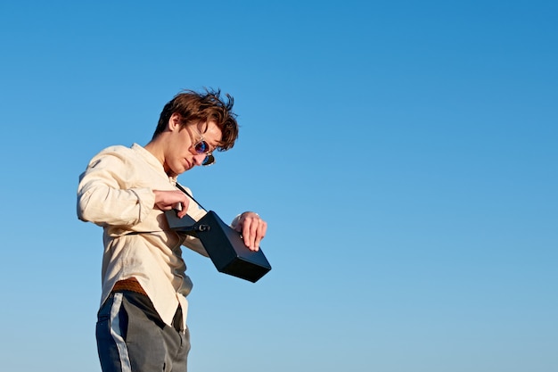 A Caucasian man from Spain standing and putting something in his black handbag on sky background