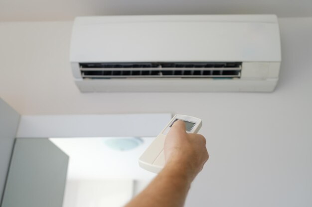 Caucasian man hand with remote control directed on the conditioner