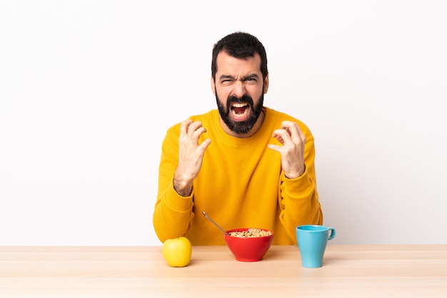 悪い状況でイライラしたテーブルで朝食を持っている白人の男