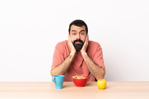 Uomo caucasico facendo colazione in un tavolo frustrato e che copre le orecchie