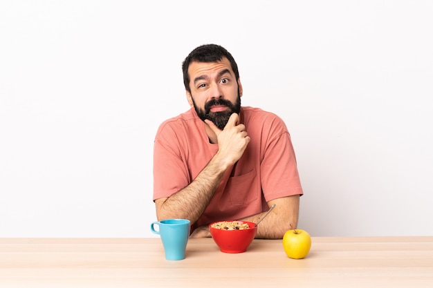 Caucasian man having breakfast in a table having doubts.