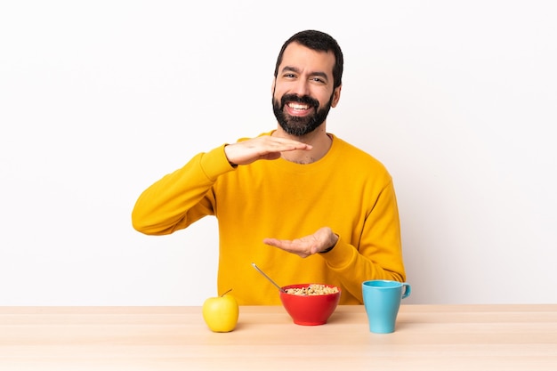 Caucasian man having breakfast in a table holding copyspace imaginary on the palm to insert an ad.