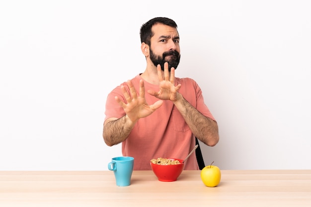 Caucasian man having breakfast in a table nervous stretching hands to the front