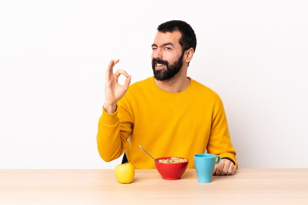 Caucasian man having breakfast in a table showing ok sign with fingers.