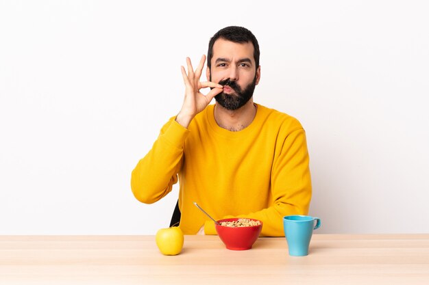 Caucasian man having breakfast in a table showing a sign of silence gesture
