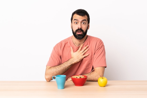 Caucasian man having breakfast in a table surprised and shocked while looking right.