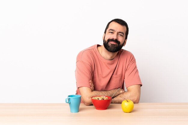 Caucasian man having breakfast in a table with arms crossed and looking forward.