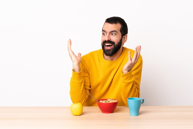 Caucasian man having breakfast in a table with surprise facial expression.