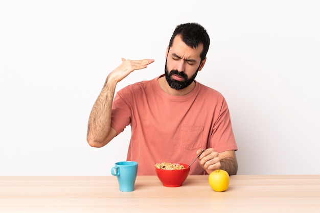 Caucasian man having breakfast in a table with tired and sick expression.