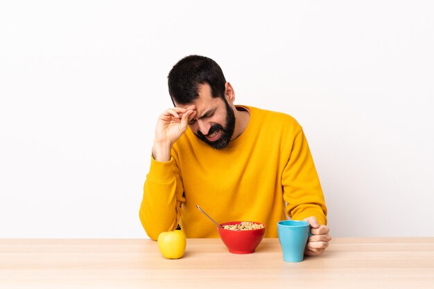 Caucasian man having breakfast in a table with tired and sick expression.