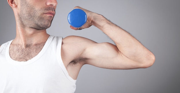 Caucasian man holding blue dumbbell.