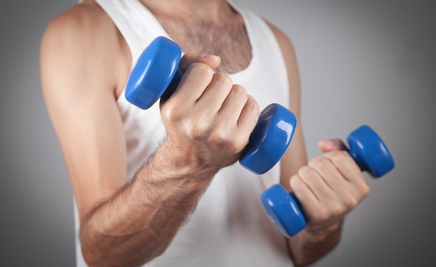 Caucasian man holding blue dumbbell.