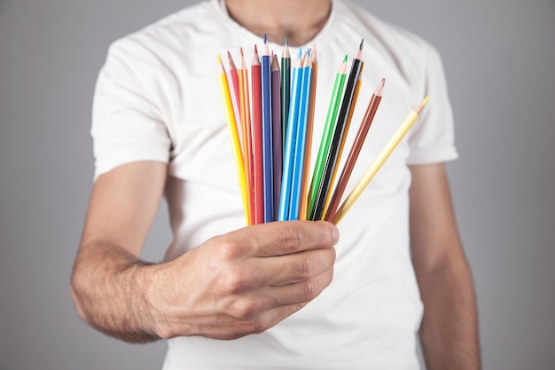 Caucasian man holding colored pencils.