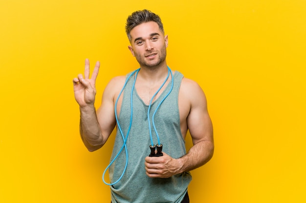 Caucasian man holding a jump rope showing number two with fingers.