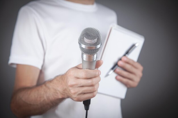 Caucasian man holding microphone notepad and pen