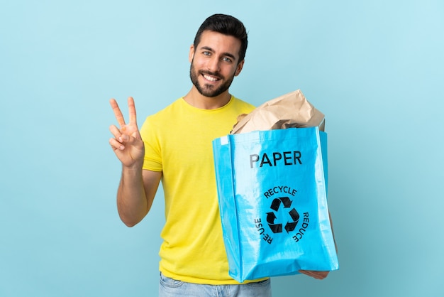 caucasian man holding a recycle bag isolated smiling and showing victory sign