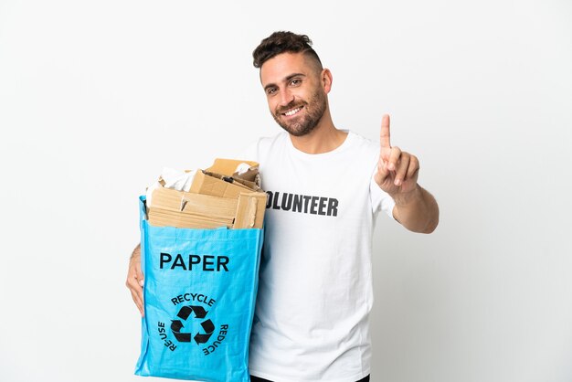 Caucasian man holding a recycling bag full of paper to recycle isolated on white background showing and lifting a finger