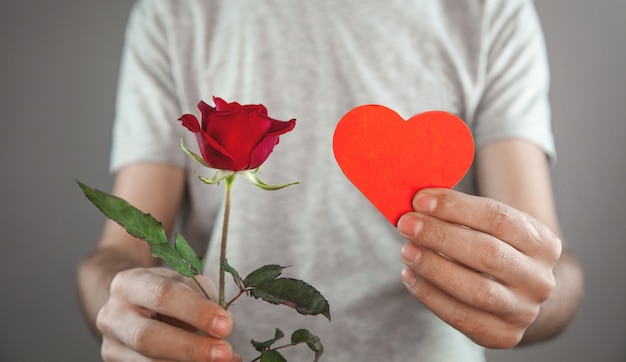 Caucasian man holding red rose flowers with red heart.