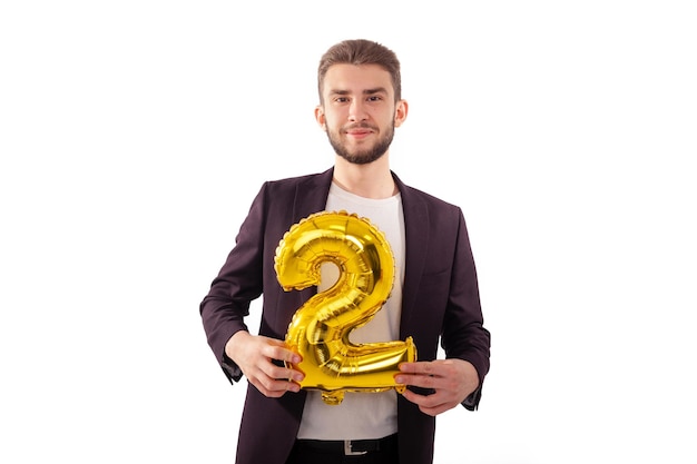 Caucasian man holding a yellow number two wearing a classic suit