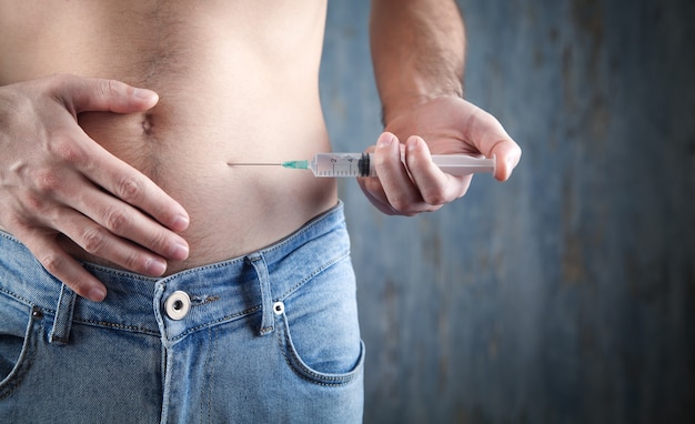 Caucasian man injecting insulin in belly.